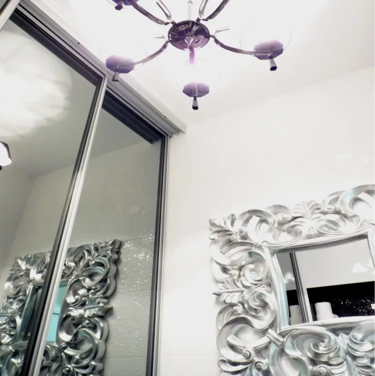 Lustro w stylu glamour z ozdobną srebrną ramą i stylowym oświetleniem sufitowym